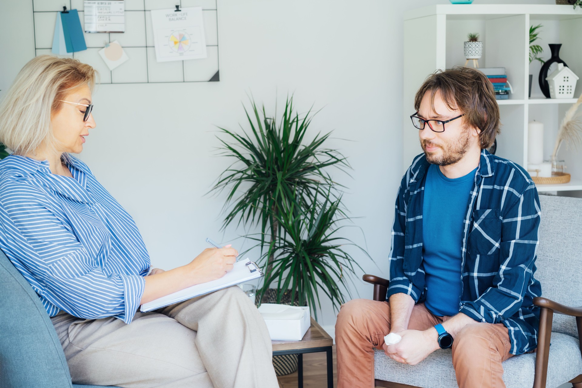 Professional psychotherapy. Female psychologist having session with male patient at mental health clinic, Taking Note During Appointment In Office. Psychological help service. Treatment of depression